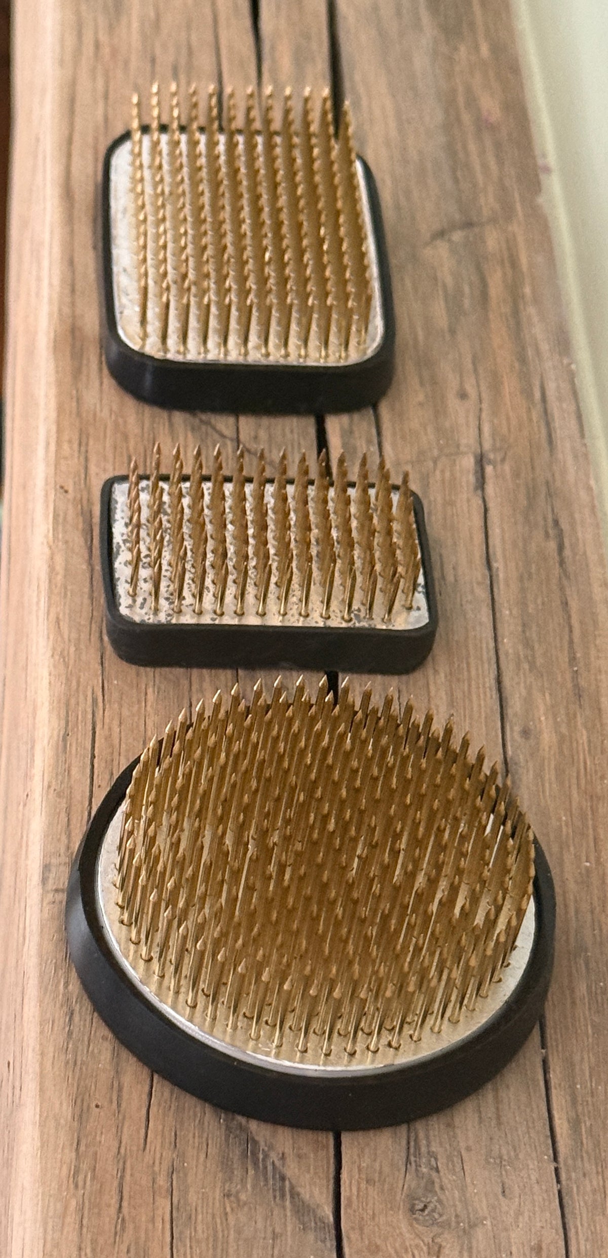 Kenzan Flower Frogs in three sizes seen from above on a wooden board