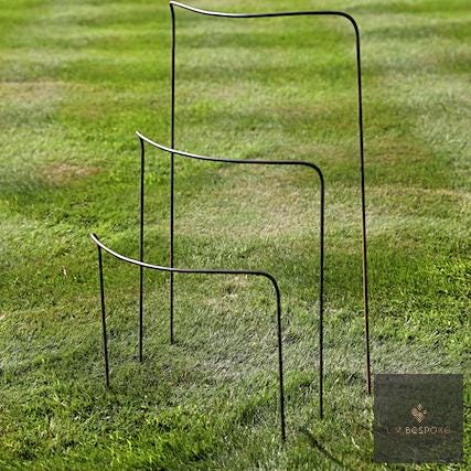 Three metal half-hoop plant supports in graduated sizes on a lawn