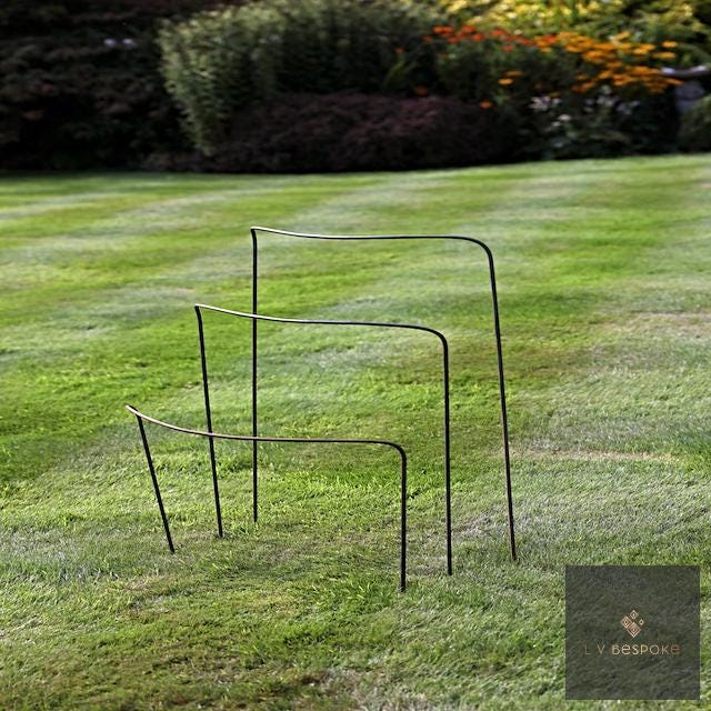 Metal half-hoop plant supports in three heights on a striped lawn