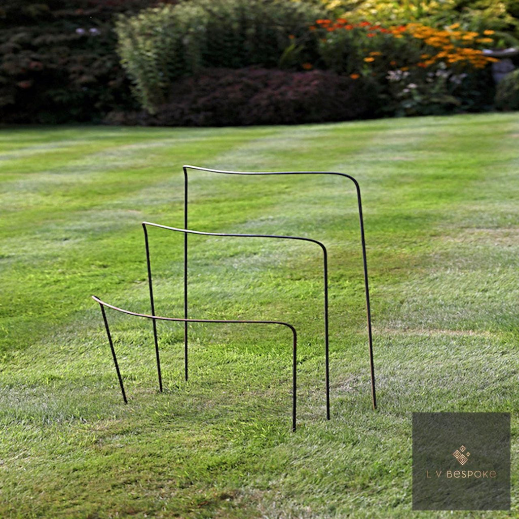 Metal half-hoop plant supports in three heights on a striped lawn