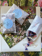 Three sachets of Larkspur Confetti on an open wedding album with petals spilling out