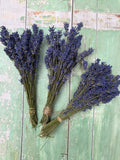 Three bundles of Bishy Barnabees Cottage Garden Ltd’s Lavender Dried (Small), tied with twine, rest on a distressed mint green wooden surface. The deep purple English lavender adds a charming, natural fragrance.