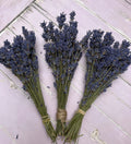 Bishy Barnabees Cottage Garden Ltd’s Lavender Dried (Small) bundles, tied with string and arranged on a light purple wooden surface, are perfect as a natural room fragrance.