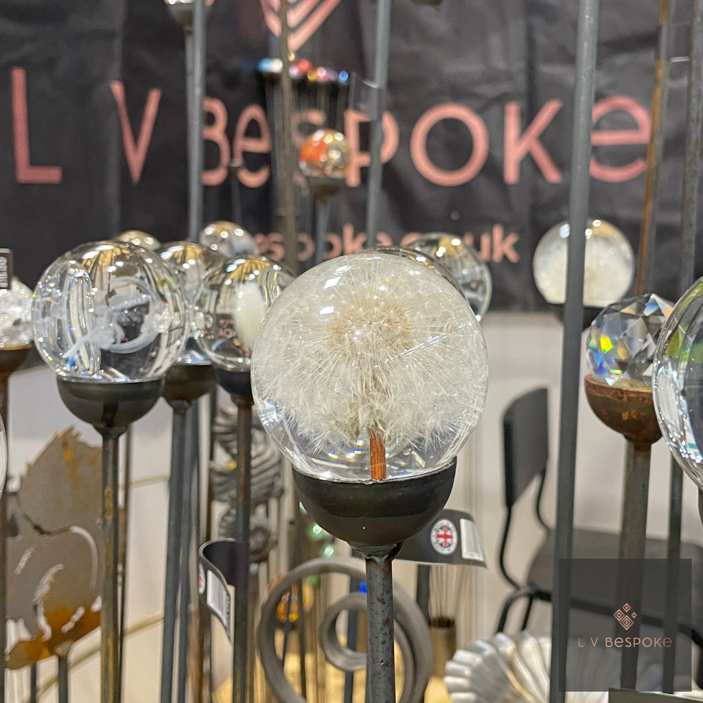 Lifelike Dandelion Garden Feature Stake standing among other glass ball stakes at a display