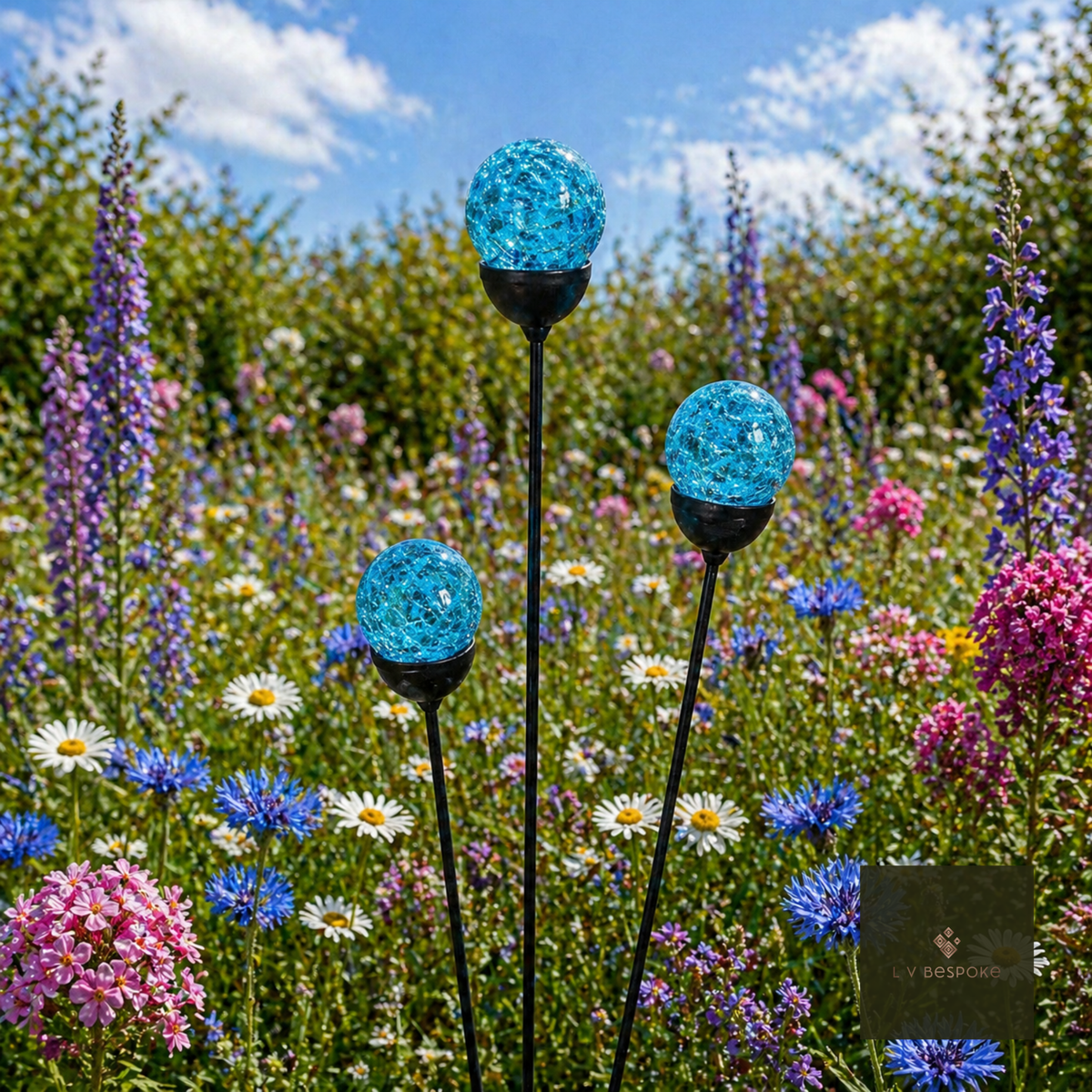 Glass Orb Cluster – three light blue crackle-glass orbs above pink and blue meadow flowers