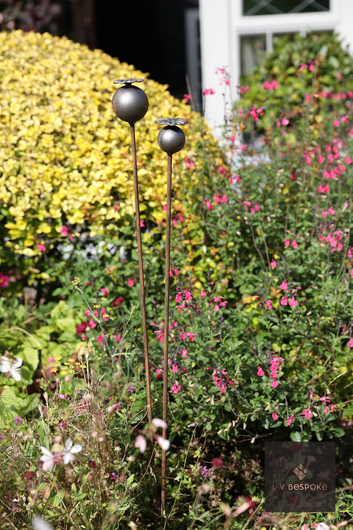 Short floral metal garden stakes – large metal poppy seed heads in a flowering border