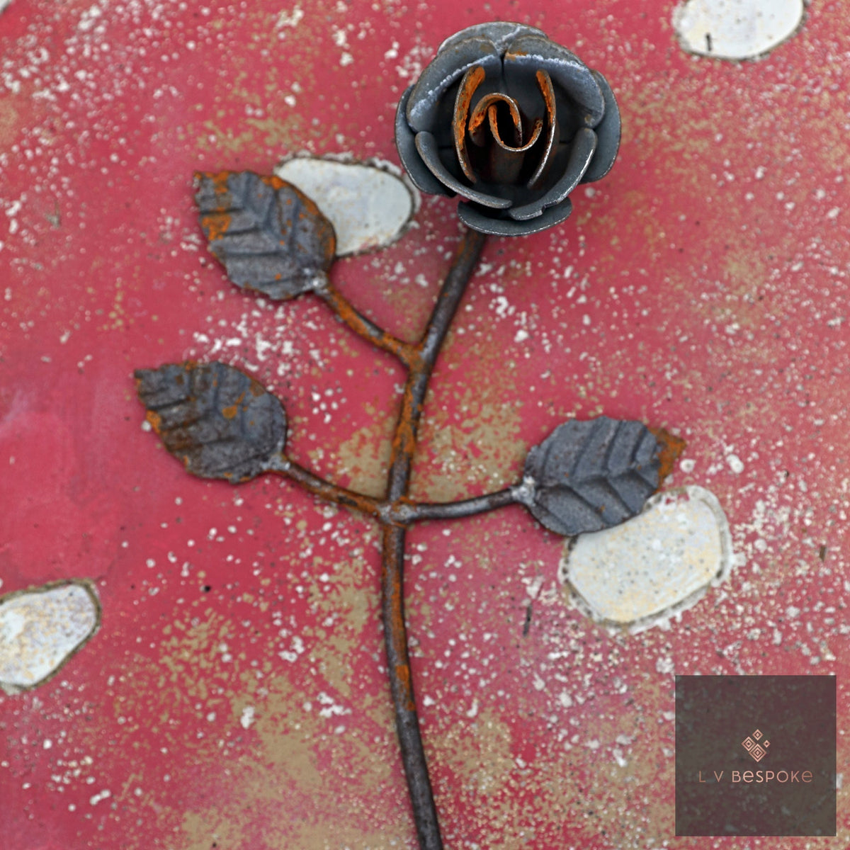 Short floral metal garden stake – metal rose with leaves against a pink wall