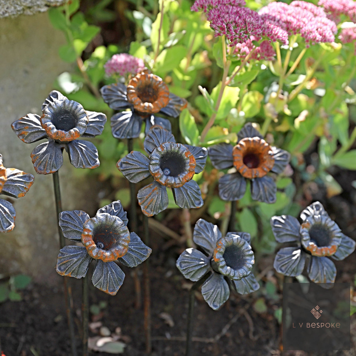 Tall floral metal garden stakes – group of blue-grey flowers with copper centres in a border