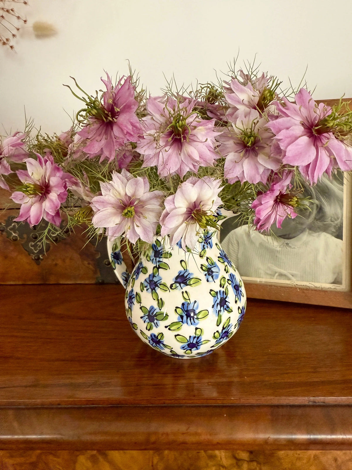 Ceramic jug of pale pink Nigella Mulberry Rose beside a framed black-and-white photo