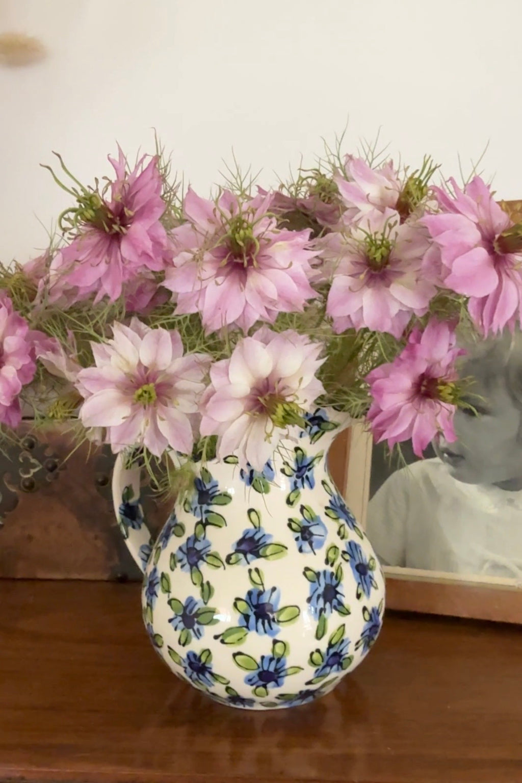 Ceramic jug of Nigella Mulberry Rose flowers and seed pods beside a sepia framed photo
