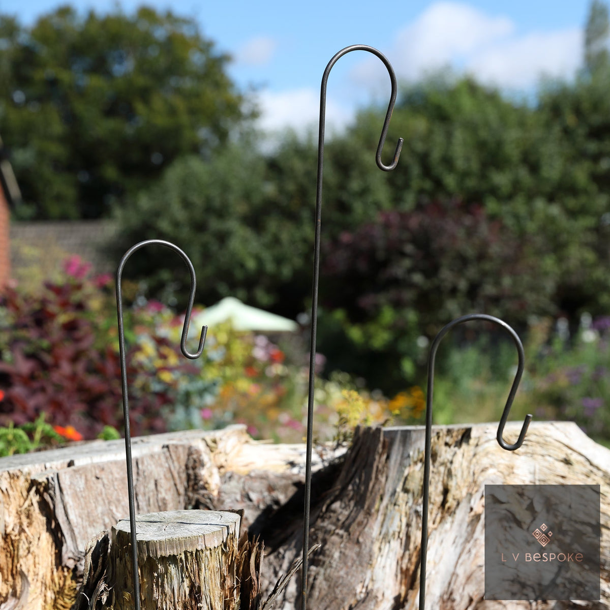 Shepherds Crook Hangers of different heights set in a tree stump in a garden