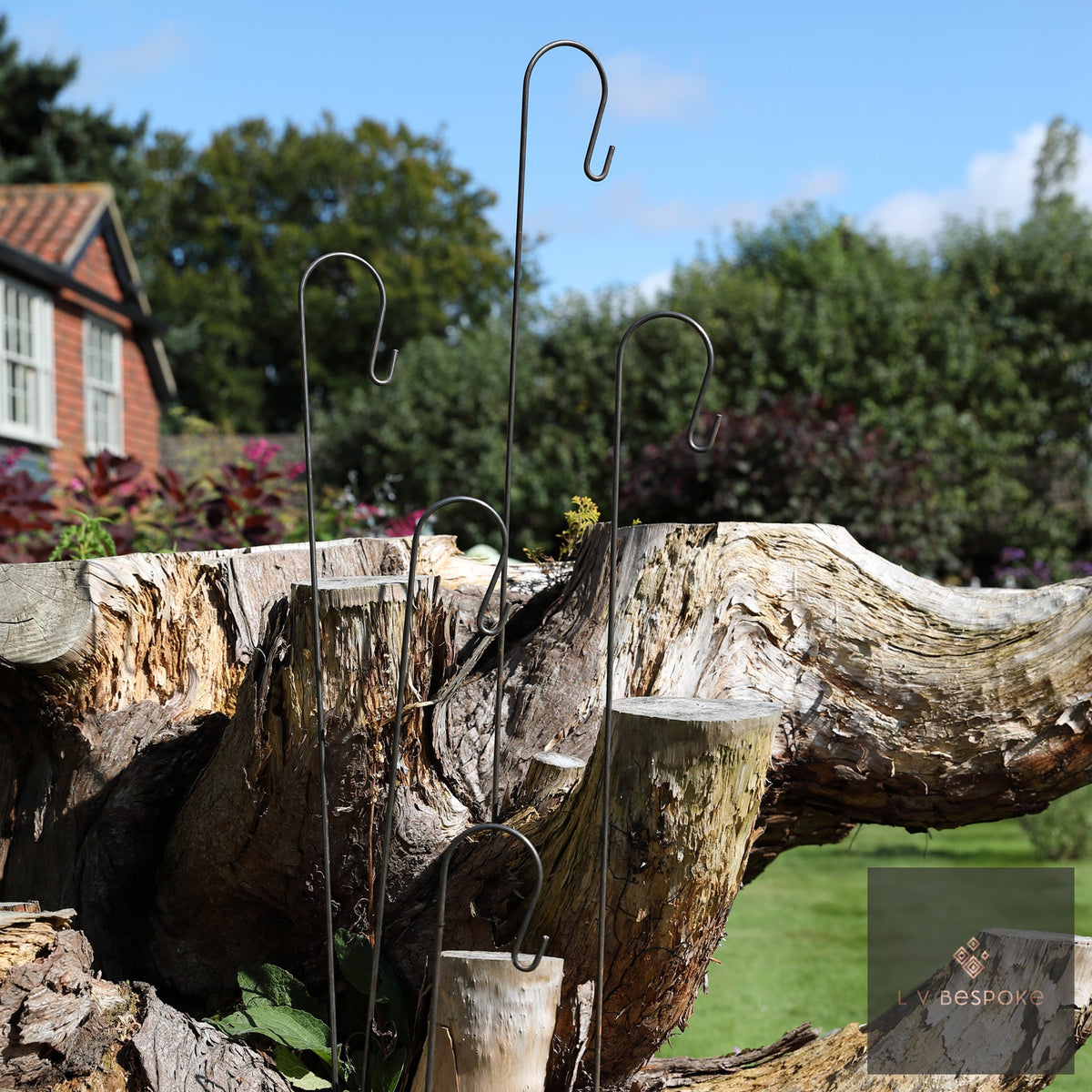 Tall Shepherds Crook Hanger against blue sky beside a weathered log