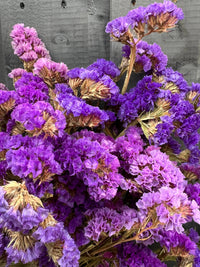 Statice Dried by Bishy Barnabees Cottage Garden features clusters of papery purple petals arranged against a dark wooden background.
