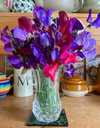 Sweet Pea Old Spice Starry Night – purple and pink flowers in a glass vase with mugs and teapot behind