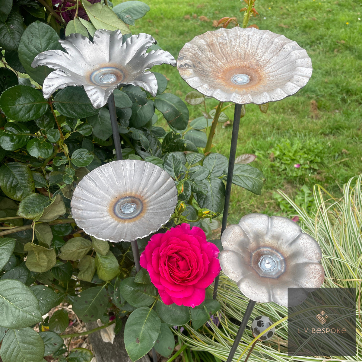 VIBee Bee Drinker – four steel flower-shaped bee drinkers on stakes beside a red rose